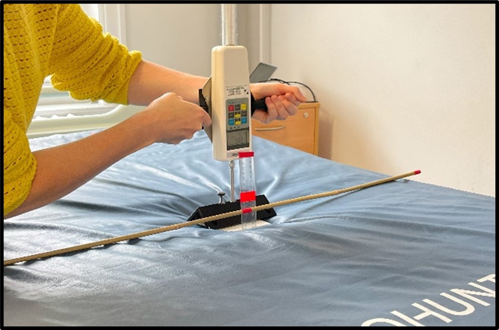 Photo of a person pressing a force gauge into a mattress to measure surface deflection